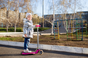 little girl riding a scooter in the Park on a Sunny spring day. Active leisure and outdoor sport...