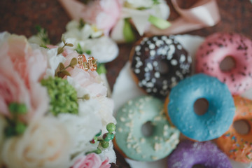 Wedding rings on flowers with colorful donuts. 