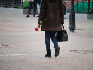 Fototapeta na wymiar Urban streets. A woman walking on the street holding a rose