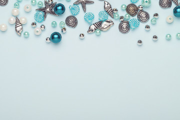 Glass, plastic, metal beads. Beads in the form of shells. Marine theme. On a blue background. The view from the top.