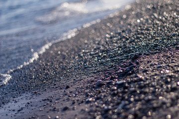 Gray black wet stones on the shore against the sea wave in Turkey. Close-up with the Sunny side.
