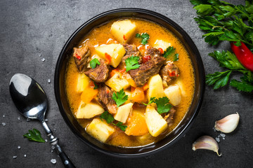 Beef stew with vegetables - carrot, ppototo and pumpkin on black