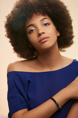 Portrait of girl with blue eyeliner, wearing T-shirt with nacked shoulder and versicolor elastic...