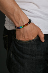 Cropped half-turn shot of man's hand with multicolor stony bracelet with semiprecious stones. The...