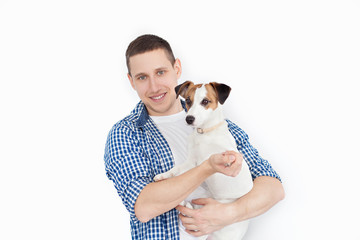 A smiling handsome man holding a purebred dog on a white background. The concept of people and animals. young man holding his dog in his arms with love and playing with him, against a white background