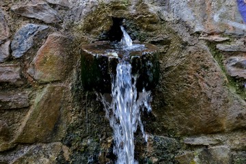 water for drinking flows from old stones close up