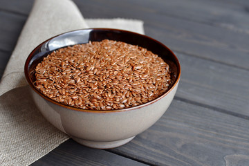 flax seeds in bowl with linen fabric on wooden background