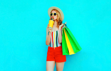 Stylish woman drinking juice holding shopping bags in colorful t-shirt, summer straw hat,...