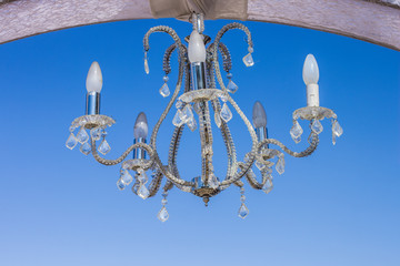 wedding chandelier interior decoration object hanging under arch in outdoor space on blue sky...