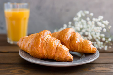 delicious breakfast with croissants, flowers and juice, good morning. Glass of refreshing orange fruit juice