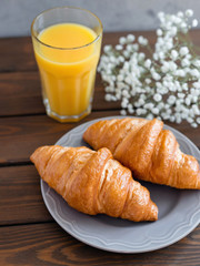 delicious breakfast with croissants, flowers and juice, good morning. Glass of refreshing orange fruit juice