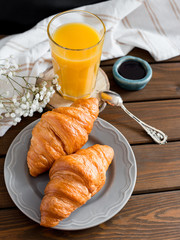 delicious breakfast with croissants, flowers and juice, good morning. Glass of refreshing orange fruit juice