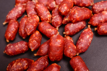 Snack to beer. Small sausages to frothy drink. Background of sausages on a dark background close-up.