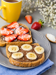 Toast with chocolate and fruits on a gray plate. Strawberries and bananas on stone kitchen table background. Top view