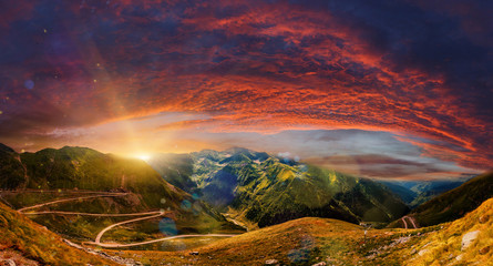 Naklejka na ściany i meble Fantastic mountain scenery. majestic sunset with dramatic sky. Colorful blooden clouds in the sky.