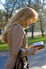 Beautiful woman looking in paper notebook while walking in the park