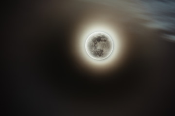 Full moon with yellow glow of sun behind it during eclipse