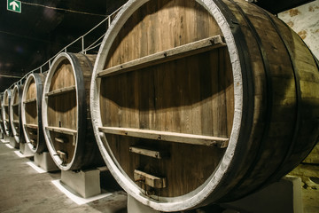 Underground wine cellar with old big wooden barrels or containers in winery