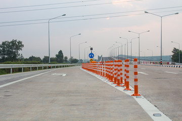 The orange traffic pole or flexible traffic bollard on asphalt road for crossroad