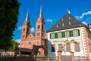 Fototapeta premium Seligenstadt's famous landmark, the Einhard-Basilika (Basilika St. Marcellinus & Petrus) with its two Romanesque Revival towers next to the former Benedictine monastery with a white Baroque façade.