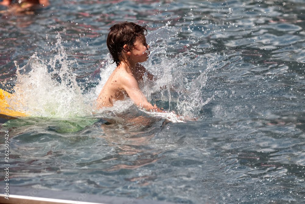 Wall mural little boy having fun in the pool in summer day. childhood and family concept.