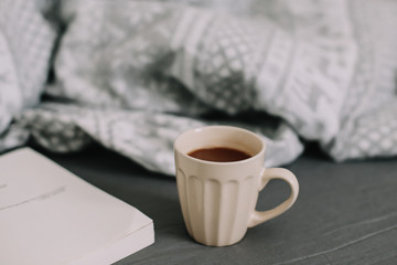 Wool beige sweater, warm knitted plaid, a book and coffee cup. Breakfast in bed. Sweet home. flat lay, still life