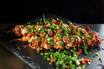 Grilled meat skewers, shish kebab on black slate.