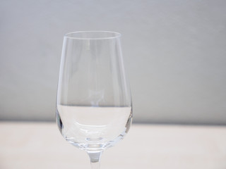 Closeup macro detail of empty Champagne flute, with gray wall background distortions reflecting on glass. Shallow focus. Fine wine and parties.