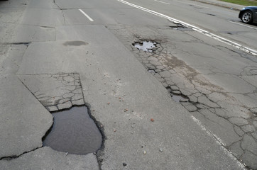 Poor condition of the road surface. Spring season. Hole in the asphalt, risk of movement by car, bad asphalt, dangerous road, potholes in asphalt.  Kiev,Ukraine