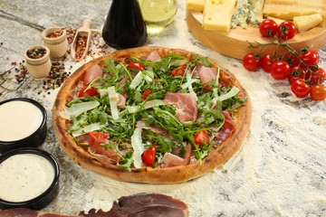Delicious pizza with mozzarella, tomato, ham and rucola
