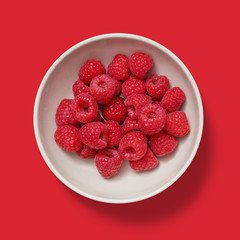 Closeup of raspberry in a white porcelain bowl isolated on red background	