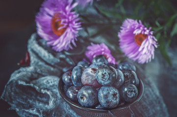 Blue berries blueberries in wicker white basket with autumn leaves in a rustic style. Close-up.