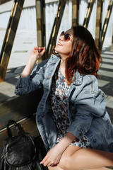 Fototapeta premium Attractive girl with sunglasses sitting on wooden bench