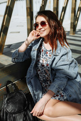 Fototapeta na wymiar Attractive girl with sunglasses sitting on wooden bench