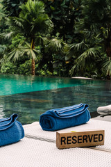 Wooden nameplate Reserved of sunbeds near swimming pool
