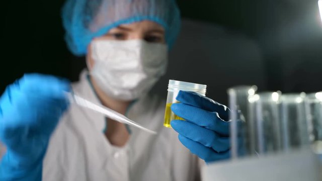 A demonstration video of a medical laboratory scientist dropping a sample of urine into a cup.