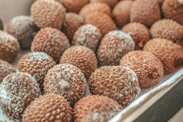 Rotten lychee fruit in a wooden drawer on a rustic wooden background. Fruits are covered with mold. Close-up
