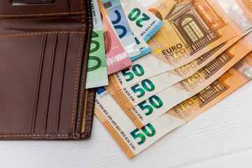 Euro banknotes with brown wallet on table