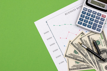 Dollar banknotes with business graphs and calculator isolated green