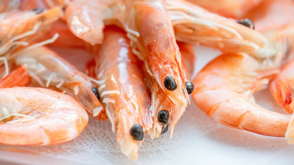 Shrimps lie on a small glass transparent plate on a bright table
