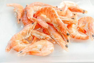 Shrimps lie on a small glass transparent plate on a bright table