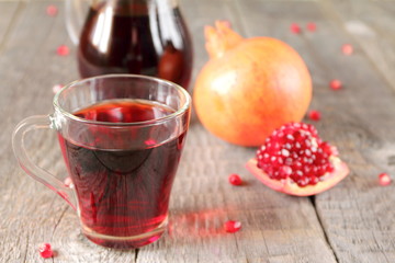 A mug of pomegranate juice on a grey wooden background.