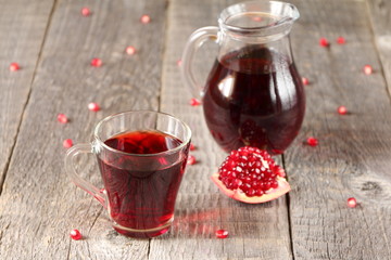A mug of pomegranate juice on a grey wooden background.