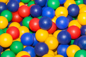 Top view colorful plastic balls in a dry pool. Plastic colorful balls for playing. Colorful plastic gum balls background in kid playroom or playground for children's holiday party concept. Close up