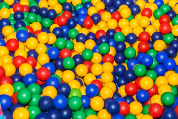 Fototapeta na wymiar Top view colorful plastic balls in a dry pool. Plastic colorful balls for playing. Colorful plastic gum balls background in kid playroom or playground for children's holiday party concept