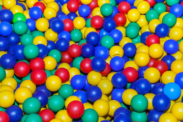 Top view colorful plastic balls in a dry pool. Plastic colorful balls for playing. Colorful plastic gum balls background in kid playroom or playground for children's holiday party concept