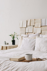Spring still life. Breakfast in bed. White bedroom. Sweet home. Books, flowers and coffee cup. flat lay 