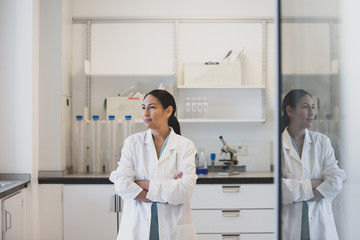 Female scientist looking out of window with reflection