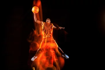 Fotobehang Play in fire. African-american young basketball player of red team in action and neon lights over dark studio background. Concept of sport, movement, energy and dynamic, healthy lifestyle. © master1305