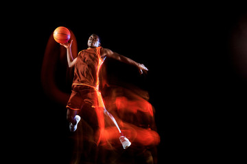 Higher than clouds. African-american young basketball player of red team in action and neon lights...